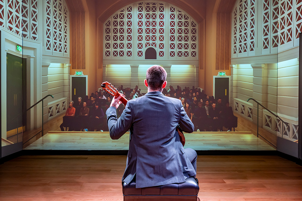 Male guitar student performing to a virtual audience.